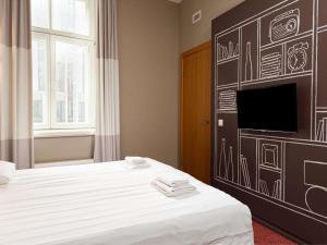 a hotel room with a bed and a tv on a wall at Ibis Riga Centre in Riga
