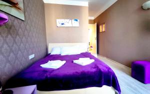 a bedroom with a purple bed with towels on it at Harmony Suites apartment 4 floor in Sunny Beach +30 photos
