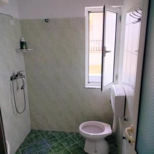 a bathroom with a toilet and a window at Adventure Beach Hostal in Durrës +13 photos