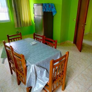 a dining room with a table with four chairs and a refrigerator at Adventure Beach Hostal in Durrës