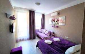 a living room with a purple bed and a couch at Harmony Suites apartment 4 floor in Sunny Beach