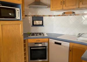 a small kitchen with a stove and a microwave at Maison Ty Bastian, 100 M² in Saint-Michel-en-Grève +16 photos