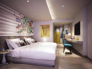 a bedroom with a large white bed and a desk at Ibis Styles Bangkok Sukhumvit 50 in Bangkok