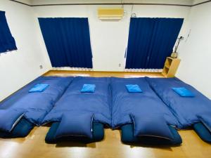 a large bed with blue pillows in a room at Guest House 楽風 in Anan