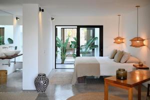 a white bedroom with a bed and a table at Casa Abora - Ocean Views, Private Pool & Sunsets in La Pared