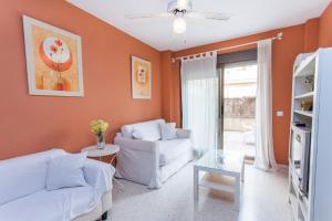 una sala de estar con paredes de color naranja y muebles blancos. en Apartamento Centro Jerez, en Jerez de la Frontera