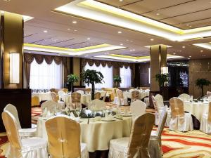 a banquet hall with white tables and chairs at Novotel Daqing Haofang in Daqing