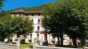 un gran edificio blanco con árboles delante de él en Résidence Grand Hôtel Appartement Standing, en Aulus-les-Bains