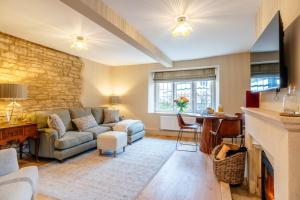 a living room with a couch and a fireplace at Beechwood Cottage | Banham Cottages in Bourton on the Water