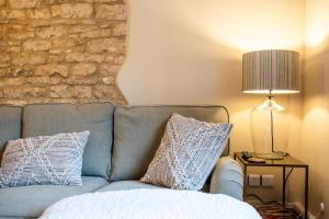 a blue couch with two pillows and a lamp at Beechwood Cottage | Banham Cottages in Bourton on the Water