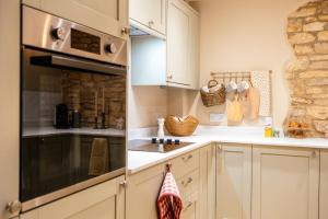 a kitchen with white cabinets and a stove top oven at Beechwood Cottage | Banham Cottages in Bourton on the Water