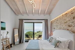 a bedroom with a white bed with a stone wall at Villa Orama Corfu in Karyótikon