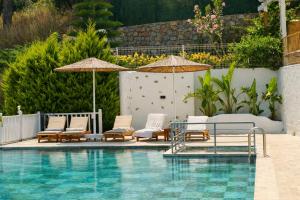 a swimming pool with lounge chairs and umbrellas at Ölüdeniz Manzara Non Alcoholic Family Hotel in Oludeniz