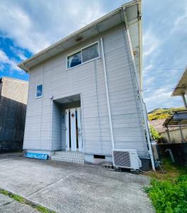 a white house with a door and a bench in front at Guest House 楽風 in Anan