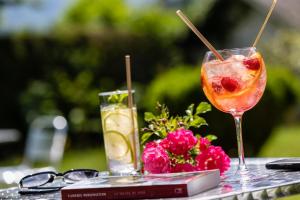 ein Tisch mit einem Getränk, einem Buch und Blumen in der Unterkunft Hotel Le Viscos in Saint-Savin