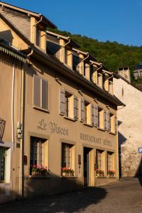 ein Gebäude mit Blumen in den Fenstern an einer Straße in der Unterkunft Hotel Le Viscos in Saint-Savin