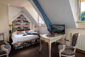 ein Schlafzimmer mit einem Bett und einem Schreibtisch mit Fernseher in der Unterkunft Hotel Le Viscos in Saint-Savin