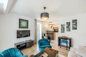 a living room with blue chairs and a tv at Appartement Élégant, Climatisation et Piscine in Ormoy-la-Rivière