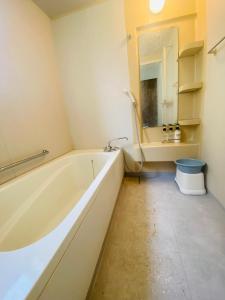 a bathroom with a tub and a sink and a mirror at Guest House 楽風 in Anan +11 photos