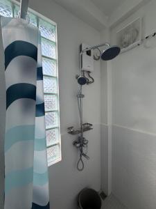 a bathroom with a shower curtain and a window at The Coast By RAD in Talisay