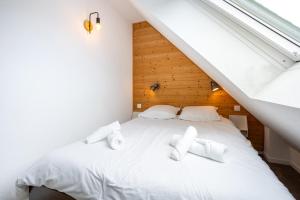 a bedroom with a white bed with white towels on it at L'Esprit Cap Coz in Fouesnant