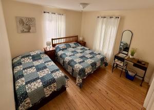 a bedroom with two beds and a mirror at Gîte de la vallee in Coaticook