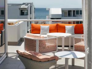 a balcony with a couch and a table and chairs at Elysium Noosa Resort - MGallery Collection in Noosa Heads