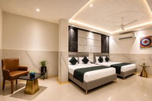 a hotel room with two beds and a chair at Hotel Delhi 37 by Star Group in New Delhi