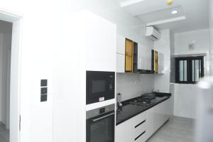 eine weiße Küche mit schwarzer Arbeitsplatte in der Unterkunft White Pole Apartments in Abuja