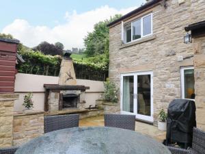 a stone house with a stone fireplace in a yard at The Chimes in Castleton