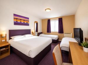 a hotel room with two beds and a desk at Stables Inn, Aintree in Liverpool +23 photos