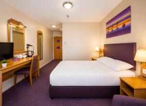 a hotel room with a bed and a desk at Stables Inn, Aintree in Liverpool