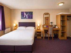 a hotel room with a bed and a desk at Stables Inn, Aintree in Liverpool