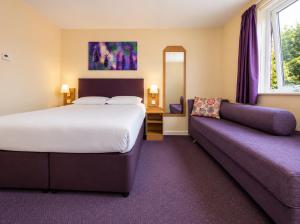 a hotel room with a bed and a couch at Stables Inn, Aintree in Liverpool