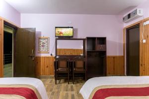 a hotel room with two beds and a flat screen tv at Hotel Monalisa Chitwan in Sauraha