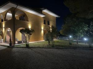 a large yellow building with lights on it at night at Markylian House in Castiglione del Lago