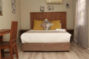 a bedroom with a bed with yellow pillows and a desk at Oria Lodge in Cape Town +14 photos