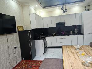 a kitchen with white cabinets and a table and a television at COMFORT house in Khiva +3 photos