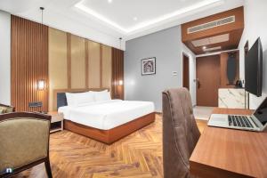 a bedroom with a bed and a desk with a laptop at Northern Residency in Srinagar
