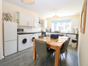a kitchen with a wooden table and white appliances at The Mill House Gardens in Lowestoft