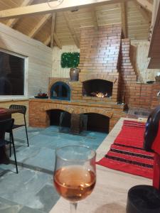 a glass of wine in front of a brick fireplace at Livada Bunicilor in Zamfireşti
