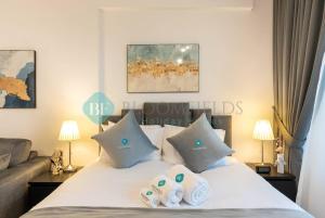 a bedroom with a bed with pillows and a couch at Bloomfields Studio in Oasis Masdar in Abu Dhabi
