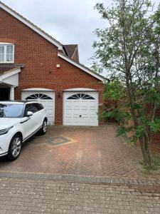 a white car parked in front of a brick house at Stylish and Modern Space in Shenley Brook End