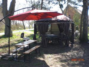 a tent with a bench and a red umbrella at Gramelowersee in Teschendorf