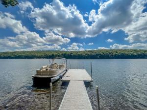 a boat is docked at a dock on a lake at Lakefront Dock Fire Pit Hot Tub Value in Swanton