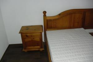 a bed with a wooden frame and a wooden night stand at Gramelowersee in Teschendorf
