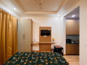 a bedroom with a bed and a tv and a kitchen at The Amberwood Escape in Greater Noida
