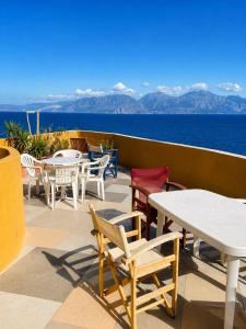 a patio with tables and chairs and the ocean at Horn Agios Nikolaos in Agios Nikolaos