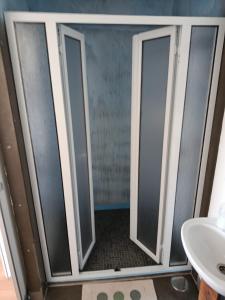 a bathroom with three glass doors and a sink at GarçaView in Vila Franca do Campo