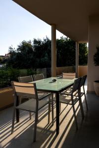 a glass table and chairs on a patio at Nataly's Gardens with Pool Lagonissi in Lagonissi